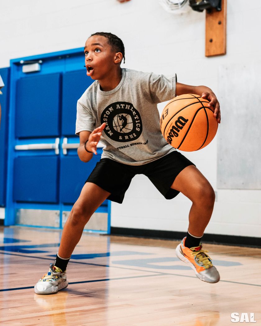 A young player in a low stance, protecting the ball, at the Marston Athletics and RH2 summer camp