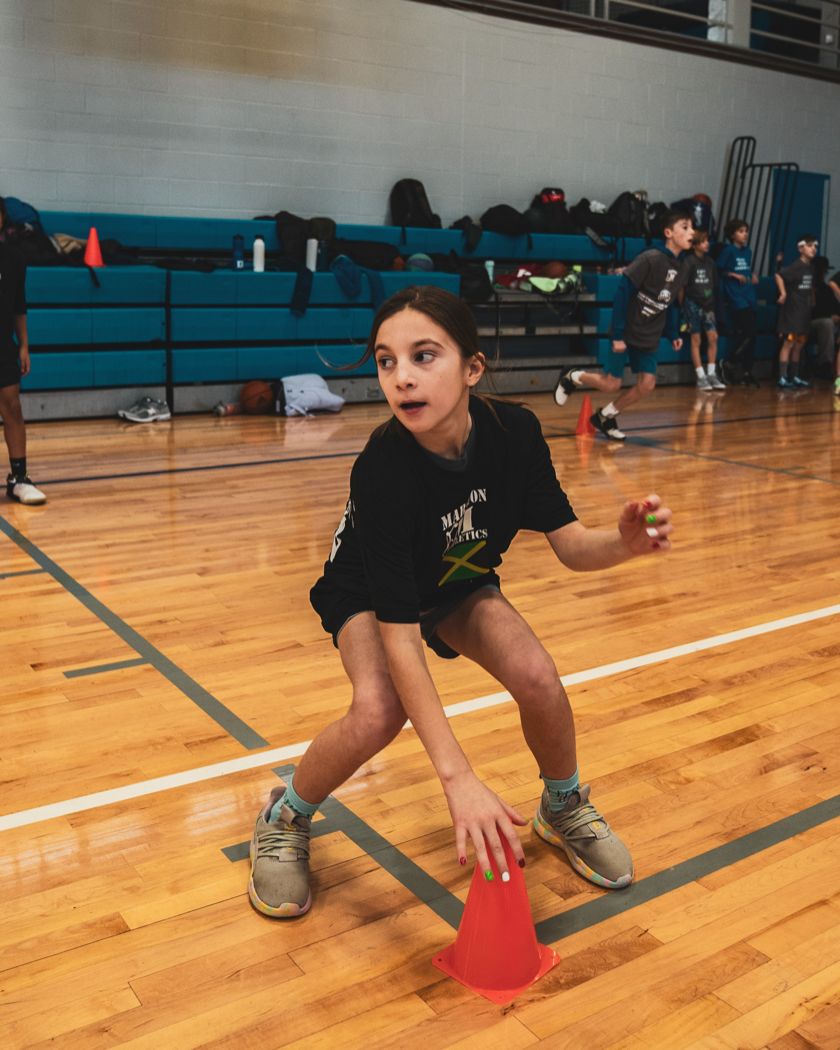 A young player in a defensive stance beside a cone at a Marston Athletics clinic
