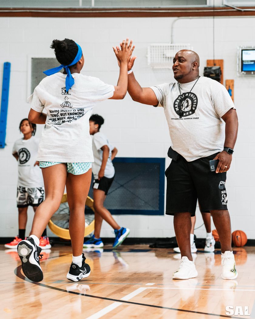 Coach Pete high-fives a camper at the Marston Athletics and RH2 summer camp
